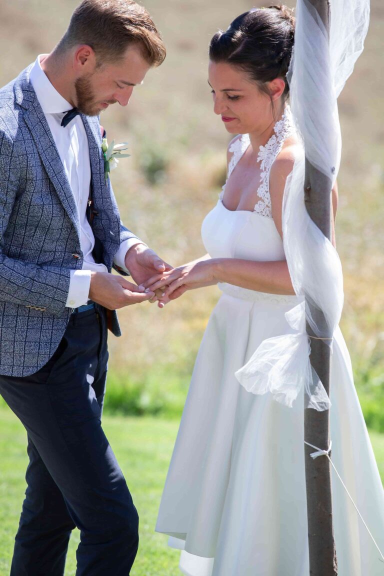 Ein Bräutigam steckt der Braut während der Trauung den Ehering an.