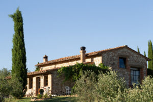 Steinhaus mit Ziegeldach und Zypressen im warmen Abendlicht in der Toskana